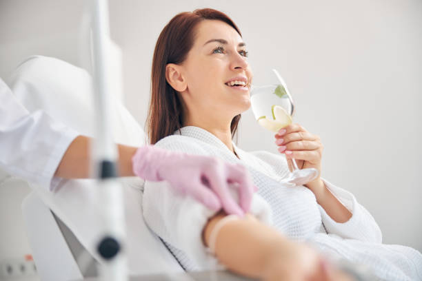 istockphoto-1270488640-612×612 Joyous female patient drinking a healthy beverage during a medical procedure in a beauty clinic